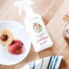 A bottle of fruit and vegetable wash is placed on a wooden surface next to a plate with peaches and a striped cloth. Produktbild-Vorschau