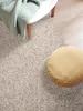 A close-up view of a rug with a blanket draped over a white table and a round cushion on the rug. Voir les images du produit