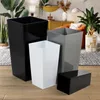 A collection of modern planters in various sizes and colors arranged on a wooden floor in a living room setting. Podgląd zdjęcia produktu