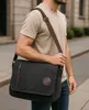 A man is walking on a street carrying a messenger bag. Podgląd zdjęcia produktu