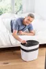 A man is in bed, reaching out to adjust an air purifier next to the bed. Produktbild-Vorschau