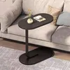 A modern side table with a dark wood-look top and a black metal base is placed next to a sofa in a living room. A small vase with flowers and a book are on the table. Náhľad obrázku produktu