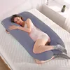 A woman is lying on a bed, using a U-shaped pregnancy pillow. Náhled obrázku produktu
