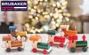 A collection of wooden train ornaments displayed in front of a blurred Christmas tree. Podgląd zdjęcia produktu