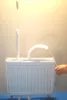 A white radiator with two cleaning tools covered in white fluffy material, one standing upright and the other curved. A hand is visible on the right side, holding a string attached to the curved tool. Anteprima dell’immagine prodotto
