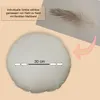 A round cushion with a measurement indicator and a feather in the background. Produktbild-Vorschau