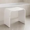 A white acrylic stool in a bathroom, next to a bathtub. Produktbild-Vorschau