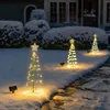 Three spiral LED Christmas trees with stars on top, decorated with lights, stand in the snow in front of a house. Voir les images du produit