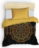 A bedding set with a gold pillow and a duvet cover featuring a gold mandala pattern on a black background, laid out on a bed with a wooden headboard. Produktbild-Vorschau