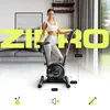 A woman stands next to a home exercise bike in a living room setting, with large yellow text overlaying the image. Produktbild-Vorschau