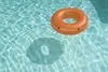 An orange inflatable ring floating on the surface of a swimming pool. Náhľad obrázku produktu