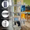 A multi-level drying rack with clothes hanging on it, set up indoors in a room with wooden floors and green walls. Voir les images du produit