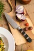 A chef's knife is placed on a wooden cutting board next to a halved red onion and cherry tomatoes. Náhľad obrázku produktu
