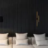 A close-up of gold decorative strips mounted on a black slatted wall, with a sofa and cushions in the foreground. Produktbild-Vorschau