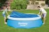 A man and a woman are putting a blue solar cover on an inflatable pool in a backyard. Produktbild-Vorschau