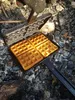 Waffles being cooked in a waffle iron over coals. Produktbild-Vorschau
