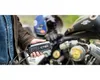 A person is holding a CTEK battery charger next to a motorcycle. Produktbild-Vorschau