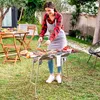 A woman is grilling food in a backyard setting. Produktbild-Vorschau