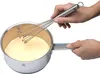 A person is whisking a yellow liquid in a silver pot. Produktbild-Vorschau