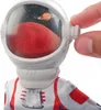 A close-up of a Barbie astronaut doll's helmet, showing a miniature scene of Mars and a ringed planet in space. A hand is adjusting a dial on the side of the helmet. Produktbild-Vorschau