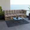 A pallet sofa with beige cushions on a balcony overlooking the ocean, with coffee tables and plants. Voir les images du produit