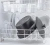 A dishwasher rack filled with dishes, including plates and a black slow cooker. Produktbild-Vorschau