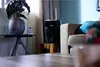 A black humidifier sits on a wooden stand next to a sofa in a living room. Produktbild-Vorschau