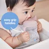 A baby is drinking from a pink sippy cup with handles. Produktbild-Vorschau