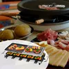 A raclette grill with food items like shrimp, salmon, vegetables, cheese, and ham, set up for a meal. Produktbild-Vorschau