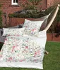 A floral patterned duvet set and pillows are laid out in a hammock in a garden setting. Produktbild-Vorschau