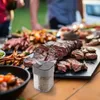 A table laden with grilled meats and side dishes, with a spice dispenser in the foreground. Produktbild-Vorschau