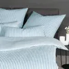 A close-up view of a bed with striped bedding and pillows. Produktbild-Vorschau