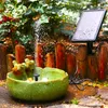 A solar-powered fountain with frog figurines in a garden setting. Produktbild-Vorschau