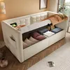 A beige upholstered sofa bed with storage is shown in a room setting, with bedding and pillows inside the storage compartment. Produktbild-Vorschau