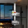 A shower caddy holding bottles of shampoo and soap is mounted on a glass shower door, with a view of a city skyline at dusk through the window. Anteprima dell’immagine prodotto
