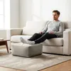 A man is relaxing on a sofa with his feet on a pouf in a living room. Produktbild-Vorschau
