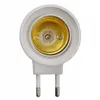 A close-up, top-down view of a white lamp adapter with a gold-colored socket and two silver prongs. Náhled obrázku produktu