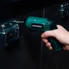 A hand holding a green and black cordless screwdriver, using it to screw a metal bracket onto a dark surface. Produktbild-Vorschau