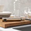 A pull-out faucet head rests on a wooden cutting board, with dishes and glasses in the background. Anteprima dell’immagine prodotto