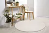 A round, light-colored rug is placed on a light wooden floor in front of a console table and a chair. A potted plant sits next to the table. Produktbild-Vorschau