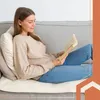 A woman is sitting on a couch and reading a book. Podgląd zdjęcia produktu