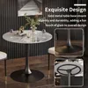 A round marble-top table with a black metal base, set in a dining area with chairs. Produktbild-Vorschau