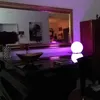 A dimly lit room with a piano, a large mirror reflecting the room, and a glowing orb lamp. Produktbild-Vorschau