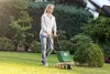 A woman is using a spreader in a garden. Anteprima dell’immagine prodotto