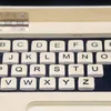 A close-up view of a wooden toy laptop keyboard with alphabet tiles. Produktbild-Vorschau