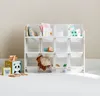 A white storage shelf unit with 12 bins, filled with various children's toys and books, placed against a light gray wall. Produktbild-Vorschau