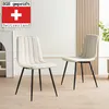 Two beige dining chairs with black legs are shown in a room with a white fireplace and a wooden slatted wall. Produktbild-Vorschau