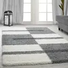 A shaggy rug with a geometric pattern in gray and white is laid out on a light gray floor in front of a doorway with sheer curtains. Náhľad obrázku produktu