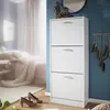 A white shoe cabinet with three flip-down drawers is shown in a bedroom setting. Produktbild-Vorschau