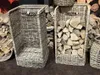 Two wicker baskets for firewood are shown, one empty and one filled with logs. Produktbild-Vorschau